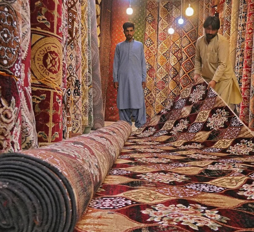 Two men are working on a carpet in a store.